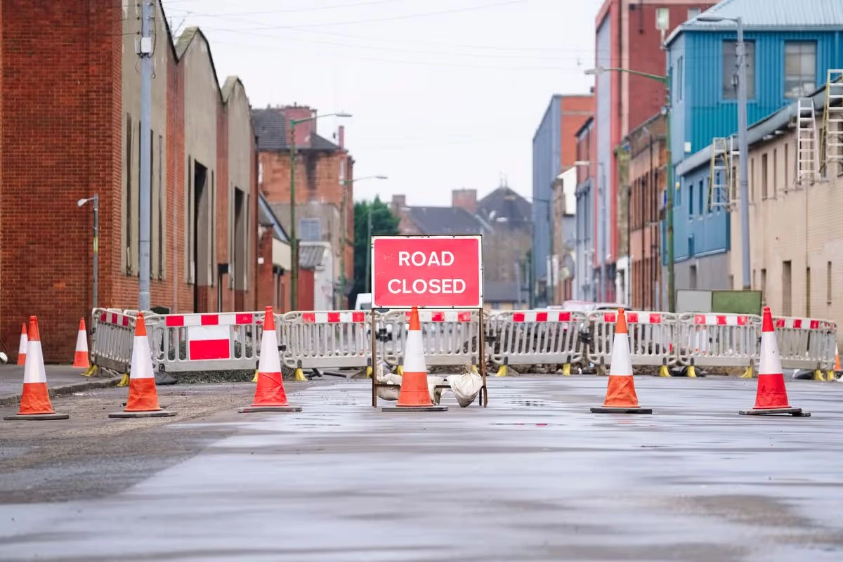 Road closed sign behind a line of traffic cones and barriers